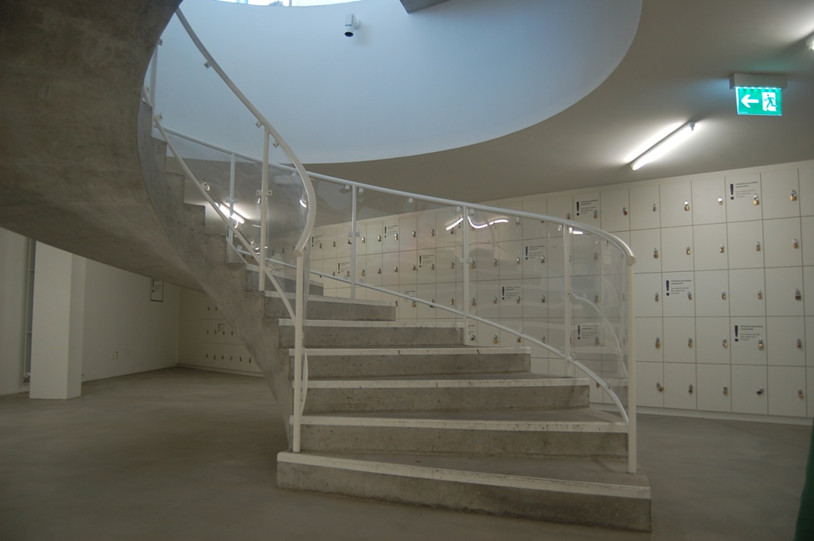 Obr. 10 Betonové schodiště vedoucí do podzemního podlaží s uzamykatelnými skříňkami v pozadí (foto: archiv autorky)